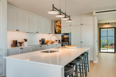 a kitchen with white cabinets and a large island with bar stools at Casa Modelo in Funchal