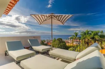 a patio with chairs and an umbrella and the ocean at Casa Modelo in Funchal