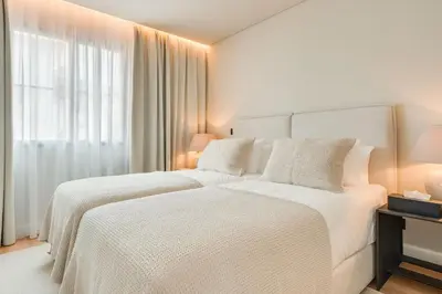 a white bedroom with two beds and a window at Casa Modelo in Funchal
