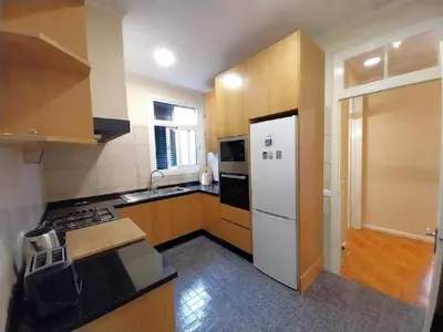 a kitchen with a white refrigerator and wooden cabinets at Recanto da Maria, by Specialstays in Funchal
