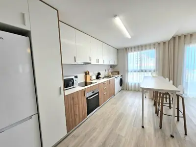 a kitchen with white cabinets and a table at Garajau Palace Sea View I in Caniço