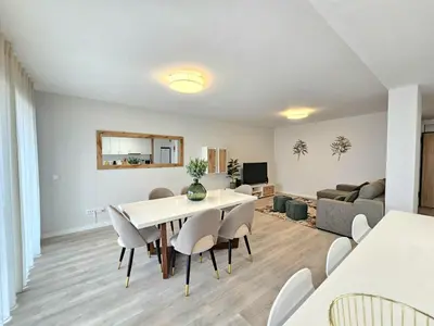 a dining room and living room with a table and chairs at Garajau Palace Sea View I in Caniço