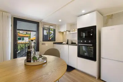 a kitchen with a wooden table and a refrigerator at Idalina's Place Funchal in Funchal