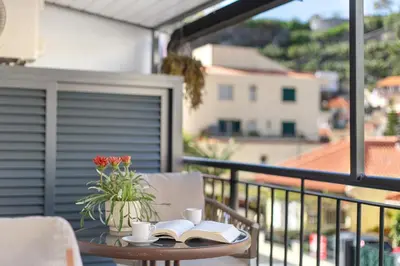 a table with books and coffee cups on a balcony at Idalina's Place Funchal in Funchal