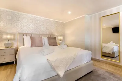 a bedroom with a large white bed and a mirror at Idalina's Place Funchal in Funchal