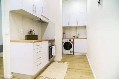 a kitchen with white cabinets and a washer and dryer at Machim by SALIM in Machico