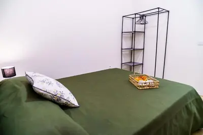a bed with a green blanket and a basket with pillows at Machim by SALIM in Machico