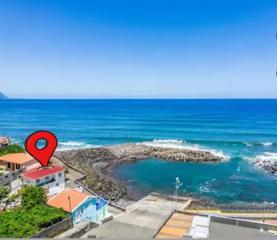 a red marker on top of a house next to the ocean at Casa Dos Avós - Sea View Studio in São Vicente