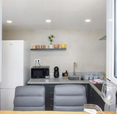 a kitchen with a counter with two chairs and a sink at Casa Dos Avós - Sea View Studio in São Vicente