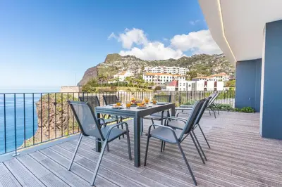 a table and chairs on a balcony with a view of the ocean at Big Cliff - Ocean View by AH in Câmara de Lobos