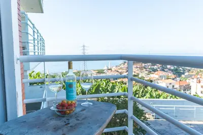 a table with wine glasses and a bowl of fruit on a balcony at Pitanga Apartment by AH in Câmara de Lobos