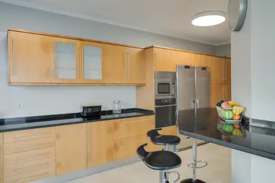 a kitchen with wooden cabinets and a counter with stools at Bay Bliss - Ocean & City View by AH in São Gonçalo