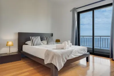 a bedroom with a large bed and a large window at Bay Bliss - Ocean & City View by AH in São Gonçalo