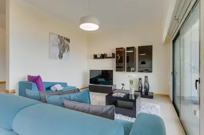 a living room with a blue couch and a table at Bay Bliss - Ocean & City View by AH in São Gonçalo