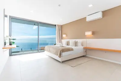 a bedroom with a bed and a large window at Villa Devaneio - Amazing Ocean View by Atlantic Holiday in Ribeira Brava