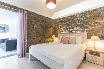 a bedroom with a large bed and a stone wall at A Casinha by Atlantic Holiday in Câmara de Lobos