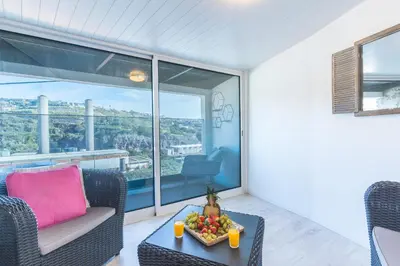 a living room with a stone wall with a clock at A Casinha by Atlantic Holiday in Câmara de Lobos