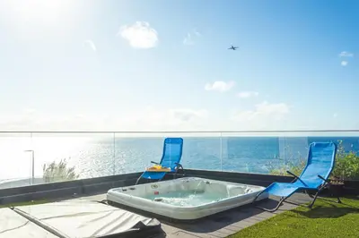 two chairs and a tub on a balcony with the ocean at Aqui ha Casa - Ocean View by Atlantic Holiday in Gaula