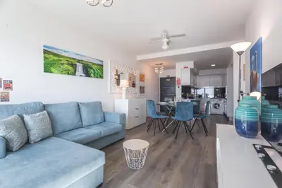 a living room with a blue couch and a kitchen at Aqui ha Casa - Ocean View by Atlantic Holiday in Gaula