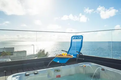 a blue chair sitting next to a tub on a balcony at Aqui ha Casa - Ocean View by Atlantic Holiday in Gaula