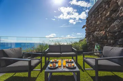 a patio with two chairs and a table with food on it at Aqui ha Casa - Ocean View by Atlantic Holiday in Gaula