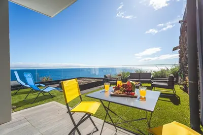a table and chairs on a patio with a view of the ocean at Aqui ha Casa - Ocean View by Atlantic Holiday in Gaula