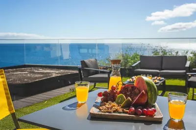 a tray of fruit on a table with two glasses of orange juice at Aqui ha Casa - Ocean View by Atlantic Holiday in Gaula