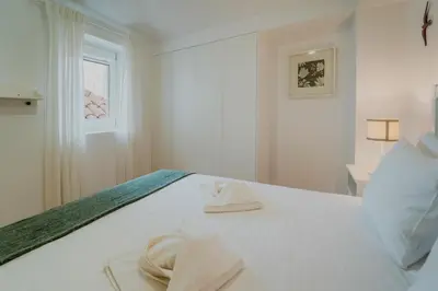 a white bedroom with a bed with a window at Casa da Levada in Funchal
