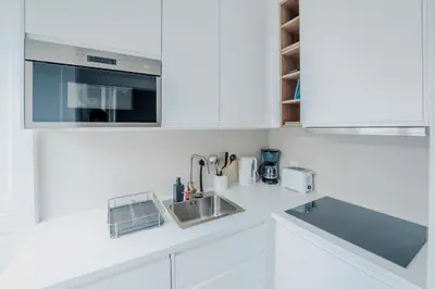 a white kitchen with a sink and a microwave at Casa da Levada in Funchal
