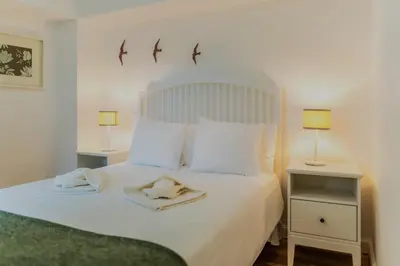 a bedroom with a large white bed with two lamps at Casa da Levada in Funchal