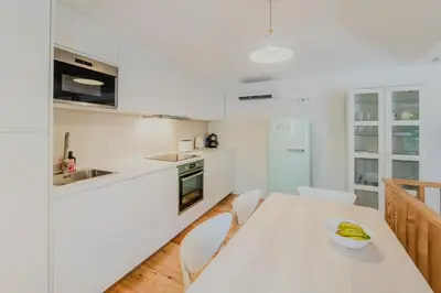 a white kitchen with a table with a bowl of bananas on it at Casa da Levada in Funchal