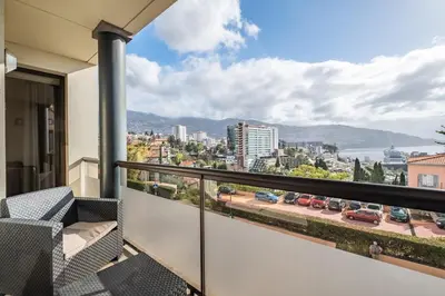 a balcony with chairs and a view of a city at Sea View 1 Bedroom Apartment Funchal in Funchal