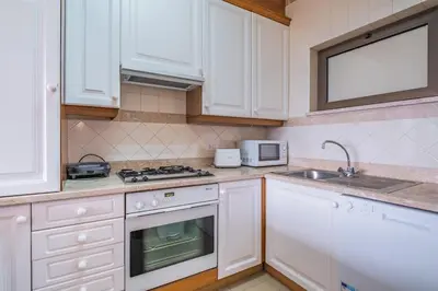 a kitchen with white cabinets and a stove and a sink at Sea View 1 Bedroom Apartment Funchal in Funchal