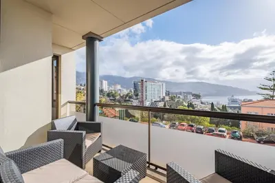 a balcony with chairs and a view of the city at Sea View 1 Bedroom Apartment Funchal in Funchal