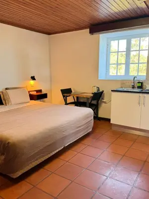 a bedroom with a bed and a table and a kitchen at Habitación con Cocina en la Montaña in Funchal