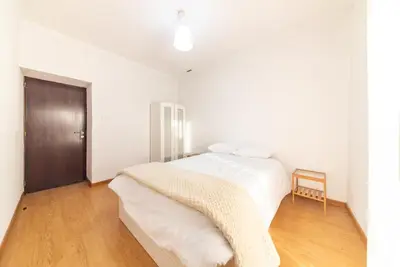 a white bedroom with a bed and a wooden floor at Abrigo dos Prazeres Guesthouse by Mth in Prazeres