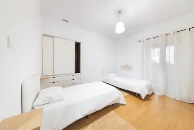 a white bedroom with two beds and a window at Abrigo dos Prazeres Guesthouse by Mth in Prazeres