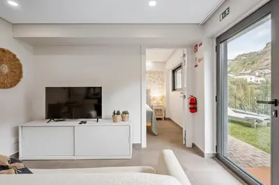 a living room with a white couch and a tv at Central Apartment Steps From Beach in Ponta do Sol