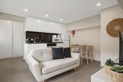 a living room with a chair and a kitchen at Central Apartment Steps From Beach in Ponta do Sol