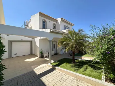 a white house with a garage and palm trees at Casa Bella - a charming holiday house in Luz in Luz