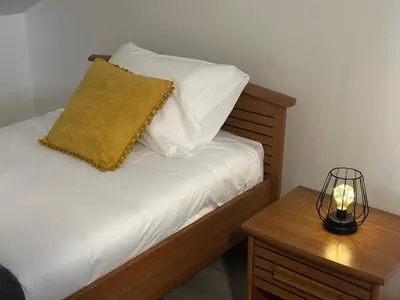 a bed with white sheets and a lamp on a table at Cantinho dos Sonhos in Santa Cruz