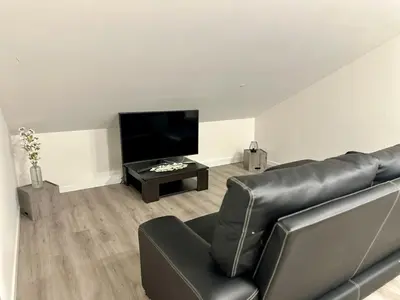 a living room with a black leather couch and a flat screen tv at Cantinho dos Sonhos in Santa Cruz