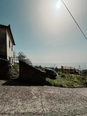 a car parked next to a house with the ocean at Madeira Island Rustic Mountain Home in Estreito de Câmara de Lobos