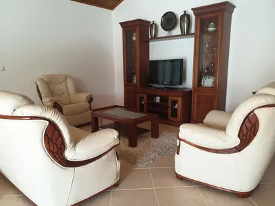 a living room with two white chairs and a tv at Farol Golfe in Ponta do Pargo