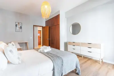 a white bedroom with a bed and a chandelier at Lido Edge View - Ocean View by Atlantic View in Funchal