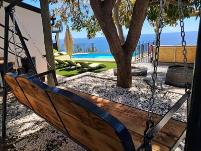 a bird perched on top of a balcony overlooking the ocean at Villa Falésia Atlântica II in Ribeira Brava