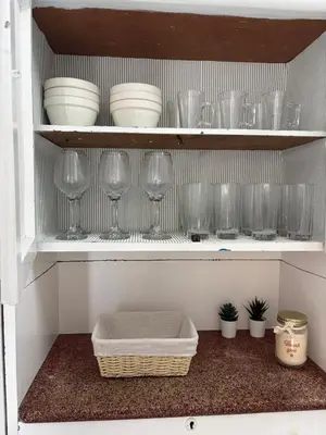 a shelf with glasses and bowls and a basket in a kitchen at Casa da Torre in Porto Moniz