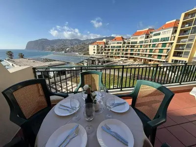 a table with wine glasses on a balcony of a resort at Formosa View in Funchal