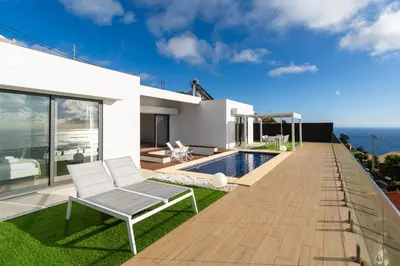 a white house with a deck and a swimming pool at GuestReady - The Ocean El Cid in Fajã da Ovelha