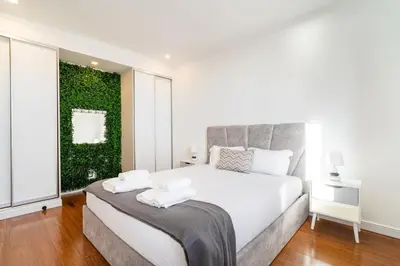 a bedroom with a white bed with a green wall at GuestReady - The Ocean El Cid in Fajã da Ovelha